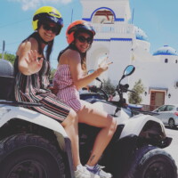 two customers smiling on a white atv in front of a white and blue church