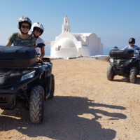 group of friends on a guided quad tour by moto manos posing in front of white church under blue skies